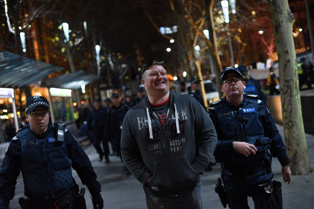 An alleged member of the United Patriot's Front is escorted from the rally by police. Photo - Finbar O'Mallon